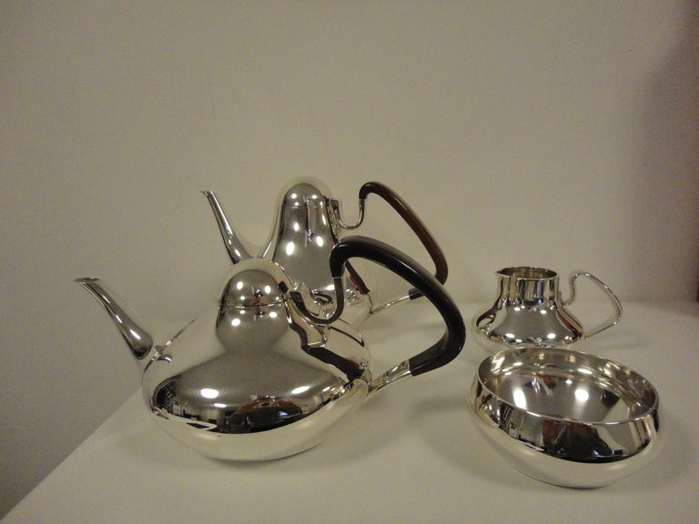 A sought after sterling silver tea and coffee set, design #1017 from 1952 by Henning Koppel. The handles on the coffee and teapots are of guaiacum, a South American hardwood. The coffee pot measures 6