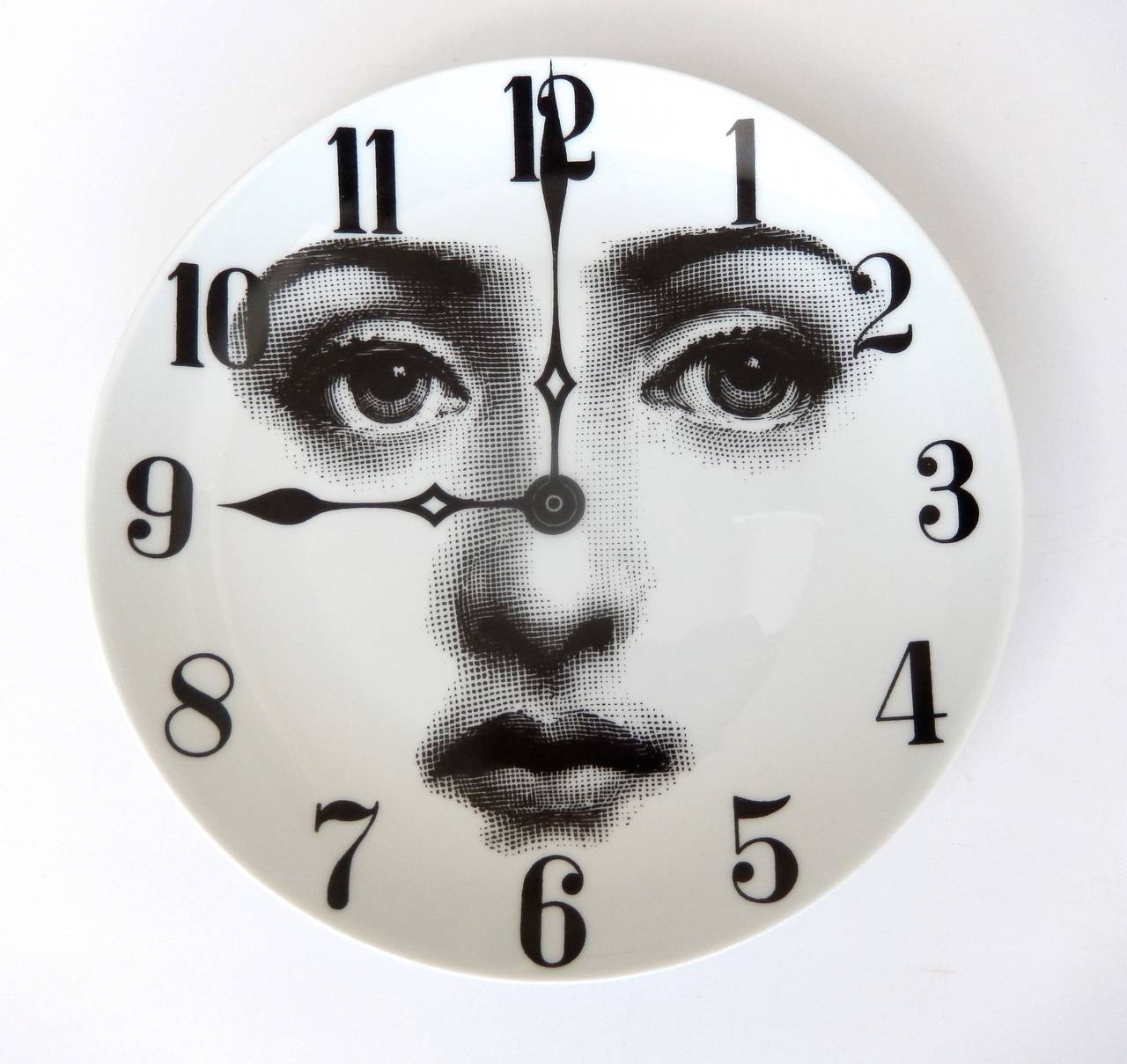 An early production plate by Fornasetti of his muse Lina Cavalieri, depicted as the face of a clock.  Whimsical, surreal design as is typical of the best of Fornasetti's graphic images.  A similar plate is illustrated on p. 198 in Fornasetti