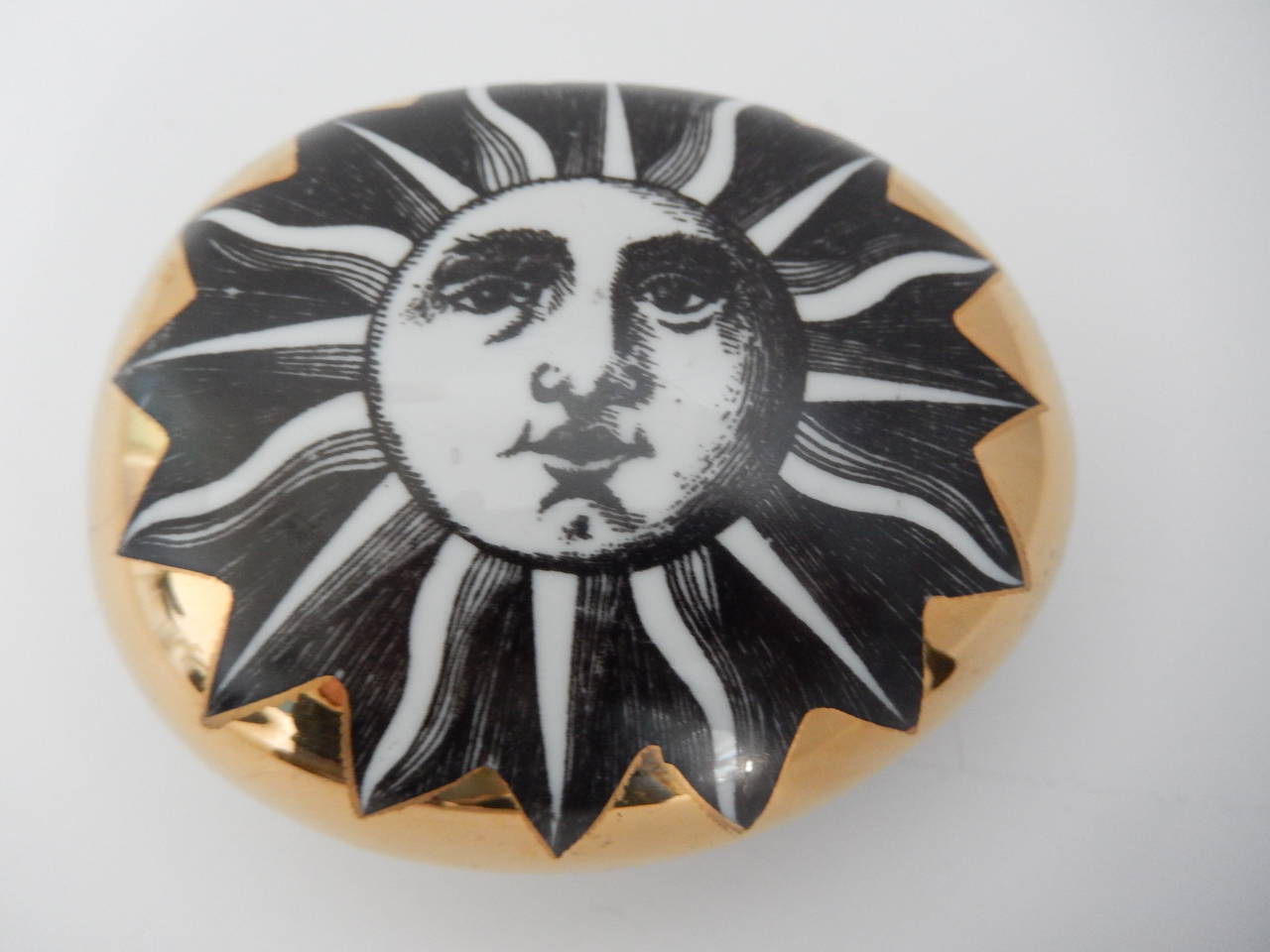 A gilded ceramic paperweight by Piero Fornasetti with a bold sun design.
An early example of his iconic sun image in excellent condition. Marked.