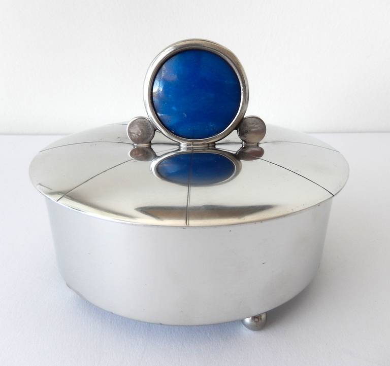 A rare, lidded pewter box with an ornamental glass finial and ball feet by Master Craftsman Rebecca Cauman (1887-1964.) A member of the Boston Society of Arts and Crafts, her metalwork has been included in exhibitions at The Brooklyn Museum, The
