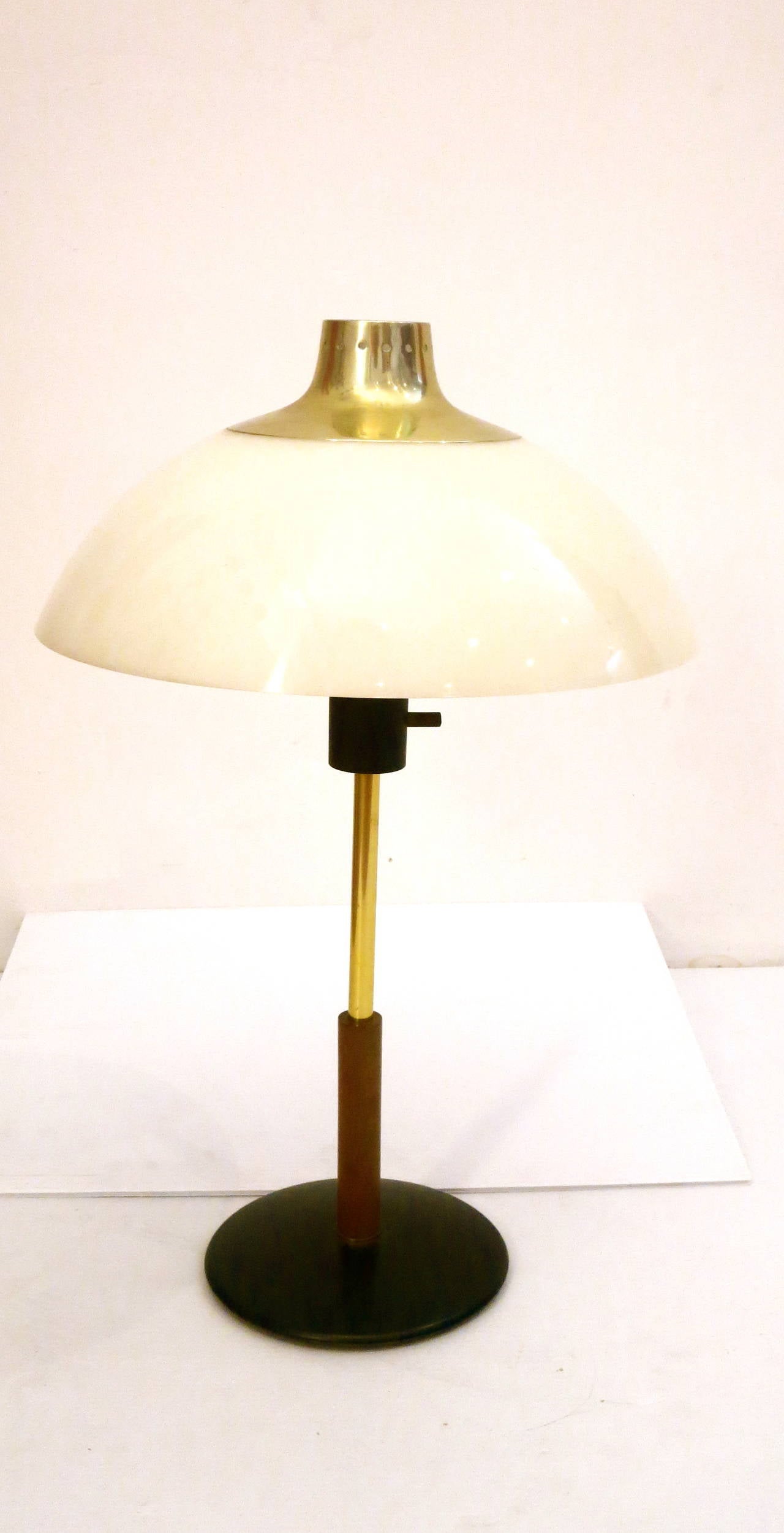 Nice and unique table or desk lamp designed by Gerald Thurston for Lightolier, circa 1950s white plastic dome with brass plated top, and walnut and brass stem with round metal base, the dome shade has very light crackling on the inside due to age