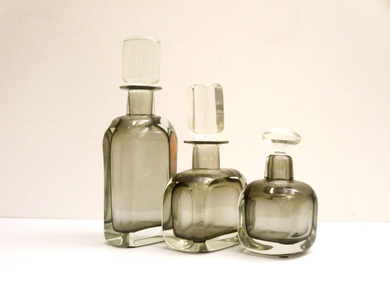 Great set of three glass decanters handblown glass, circa 1960s smoked gray glass , in Sommerso process , with clear stoppers , great condition each glass piece its thick and heavy , no chips or cracks all in different shapes and forms. The tallest