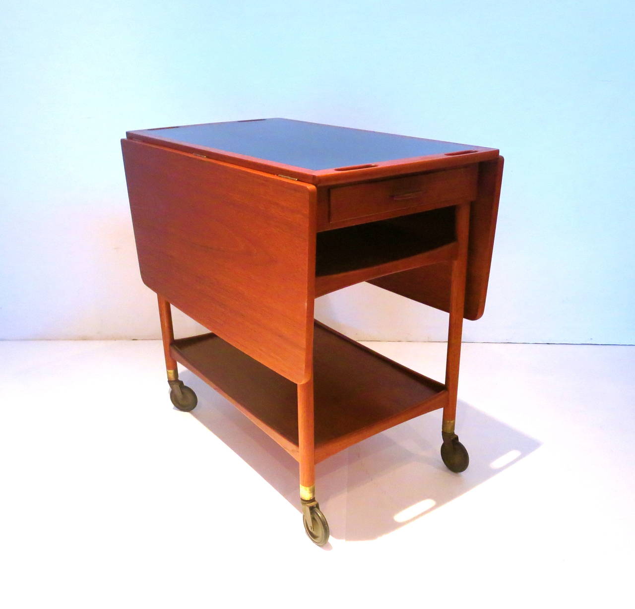 Beautiful and rare serving bar cart designed by Ludvig Pontoppidan , in 1961 simple and elegant,with drop leaf sides in teak and black laminate center top , in credible swivel top , that holds the top in place and when its not in use you swivel the