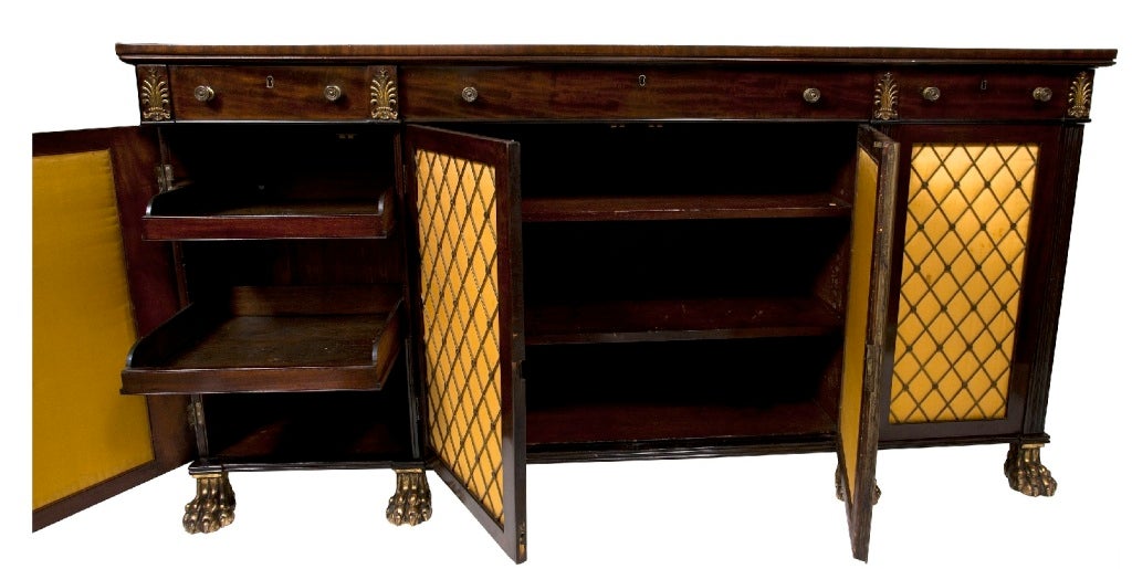 A Good late Regency/George IV Mahogany Sideboard/Cabinet circa 1830.
Well figured top with beaded moulding, three mahogany lined drawers with brass knobs flanked by brass fern leaf mounts.
Below, four brass grilled doors with silk lined panels (