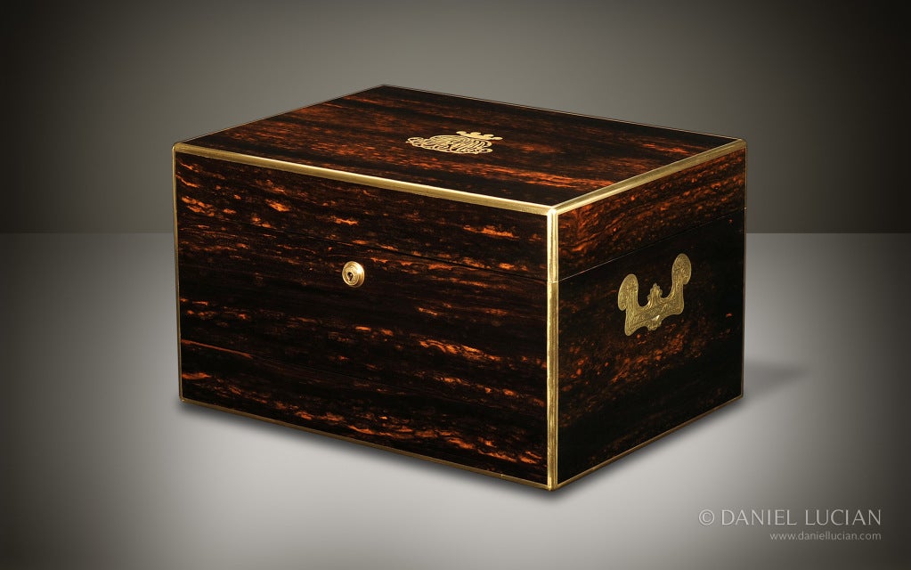 This elegant jewelry box, veneered in finely figured Coromandel, edged in brass, and with engraved ornate side handles, dates from the late 1860's. This box bears an engraved crown / coronet monogram signifying the status of its original owner. A