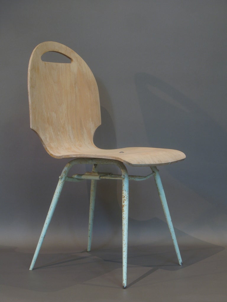 Four molded plywood chairs with unusual cut-out designs on the sides and top (forming a handle). The top is fixed to a tubular metal base, painted a light blue/green colour, with tapering splayed legs.

Very light and sturdy.