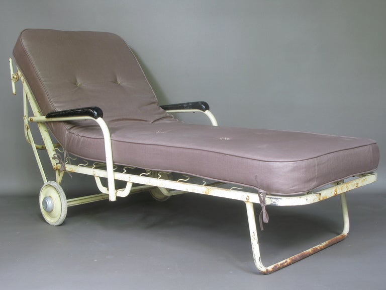 Funky sun lounger/chaise longue made of tubular metal with original off-white paint. Wooden arm rests, original rubber wheels. A new mattress covered in waxed canvas has been made for it.