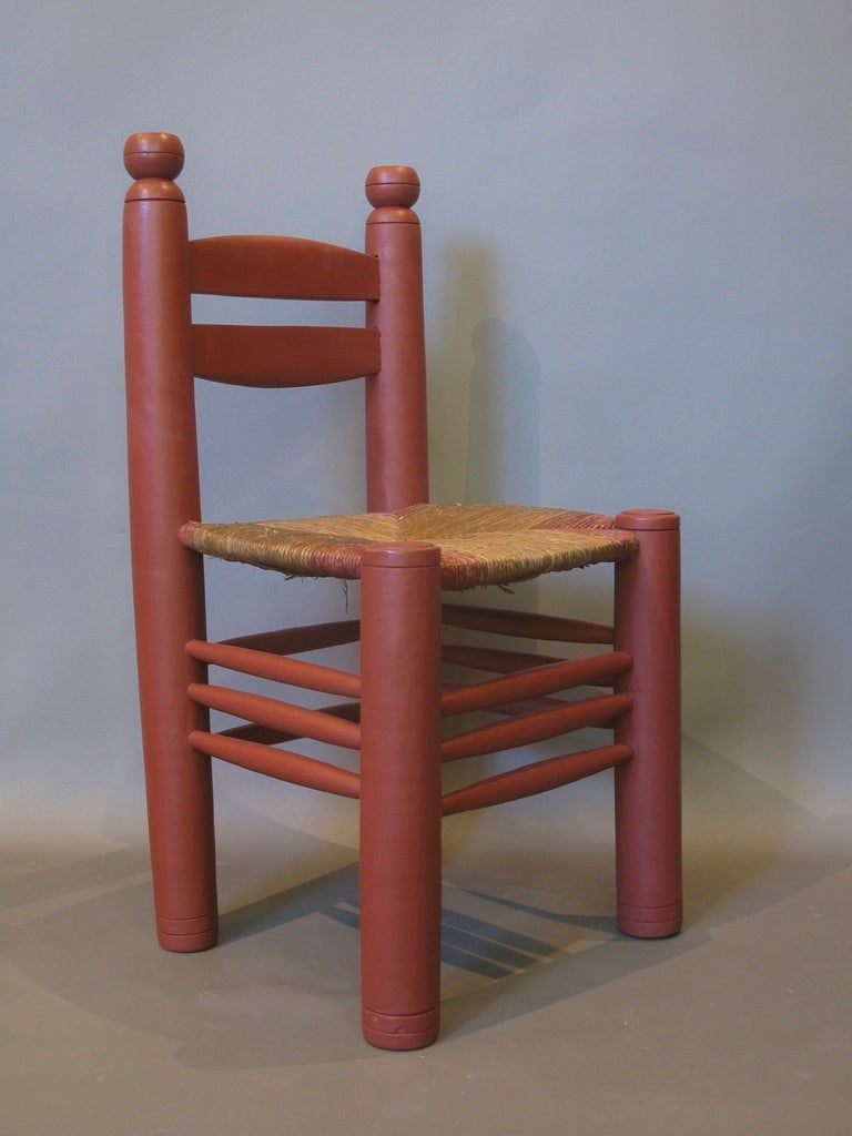 Quatre chaises robustes de grandes proportions, peintes en rouge, avec des sièges en jonc.