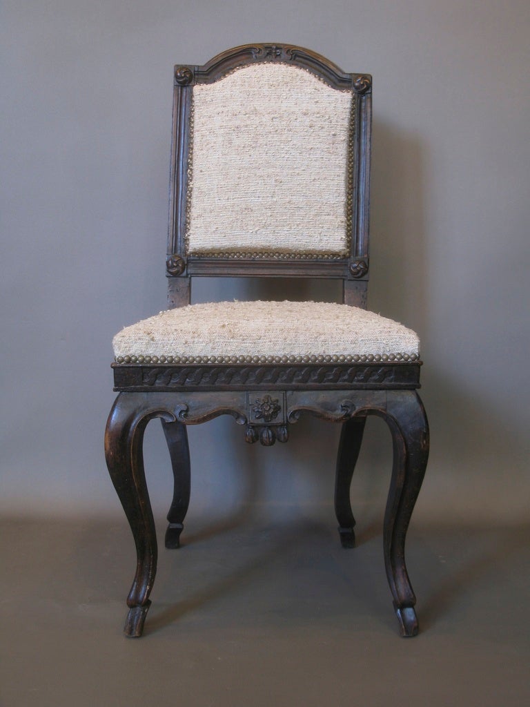 A lovely Louis XV chair with a framed back adorned with carved rosettes at each corner and additional carving on the arched crest rail. The apron is also carved with a frieze along the front and sides, and a framed rosette at the center front, with