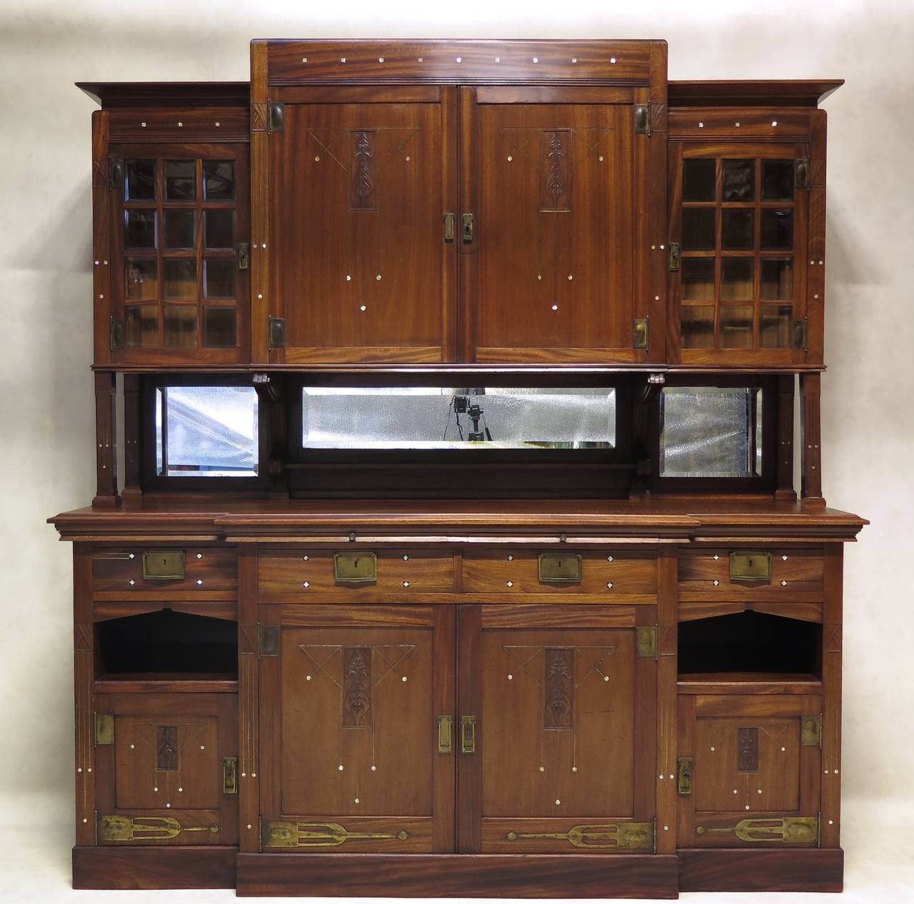 Wonderful complete dining room set in mahogany, of the Arts & Crafts or Secessionist period. Geometric motifs present throughout; carved and inlaid (brass, mother of pearl and ebony). 

Comprised of one cabinet, partially glass fronted (thick,