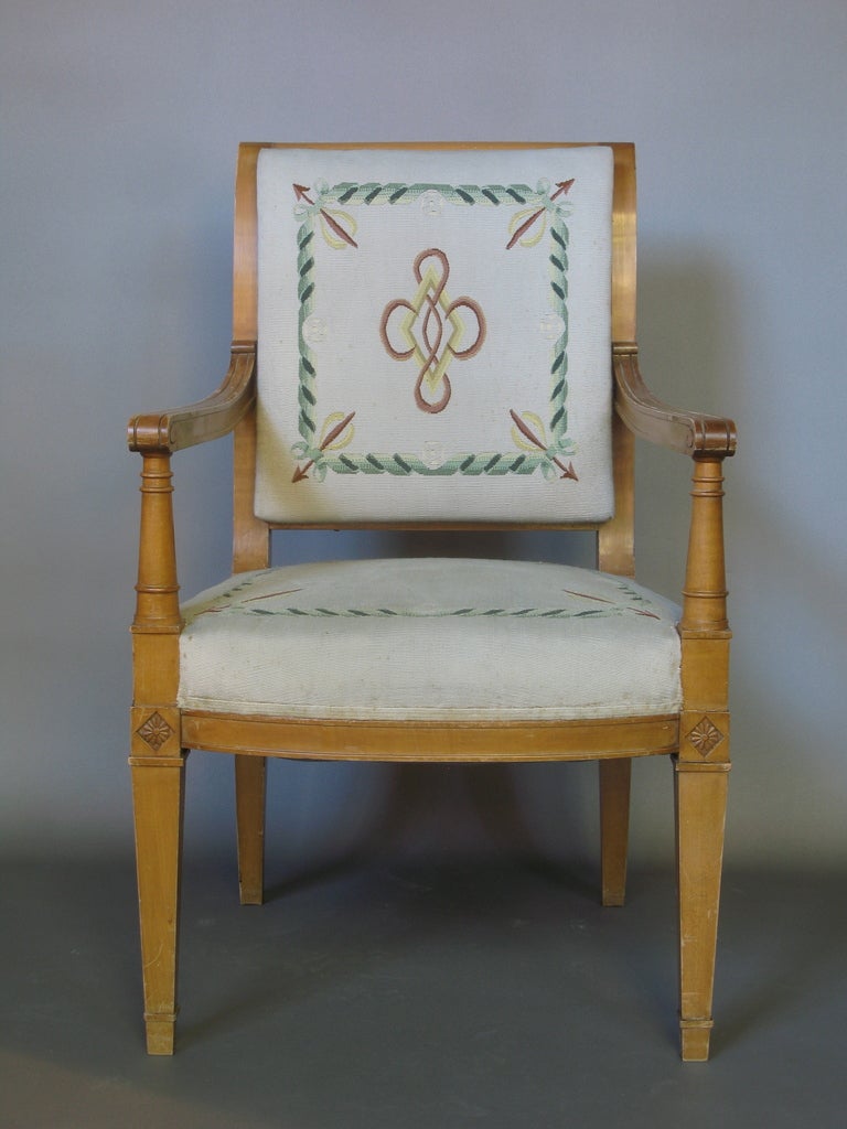 This set of armchairs is typical of the French pared-down and chic take on the Directoire style in the 1940s. 

They have a light-colored wood structure and feature wide and comfortable seats with needlepoint upholstery, scrolling crest rails,