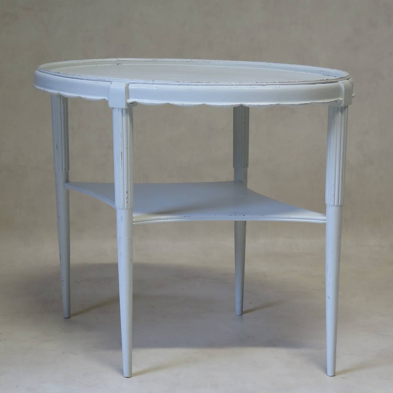 Elegant oval side table with a scalloped apron and reeded and tapering legs. Painted glossy white.