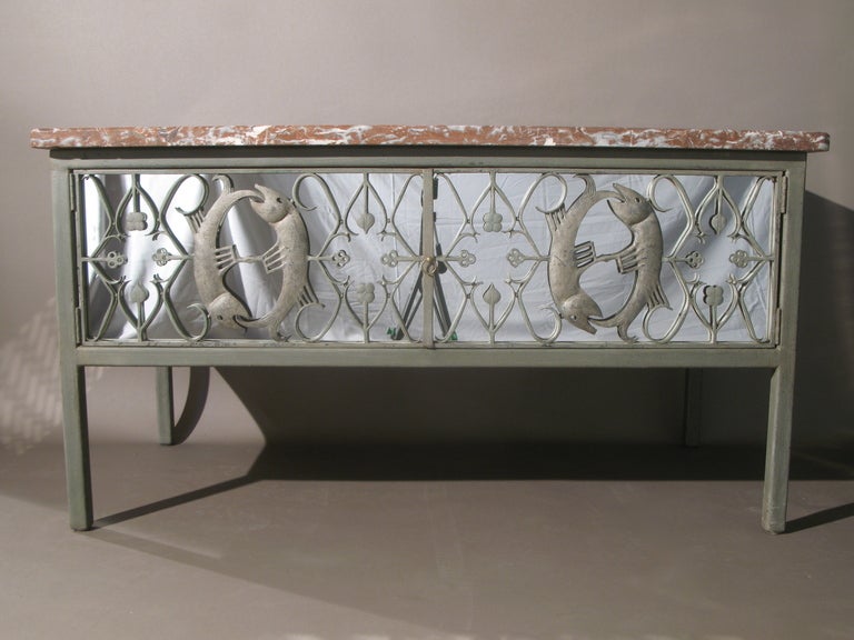 Unique metal cabinet in antique grey, adorned with two pairs of fish, head to tail, (picked out in silver) and decorative iron work on the front doors. 

The sides are encased in latticework.

The body of the cabinet is backed with mirror on all
