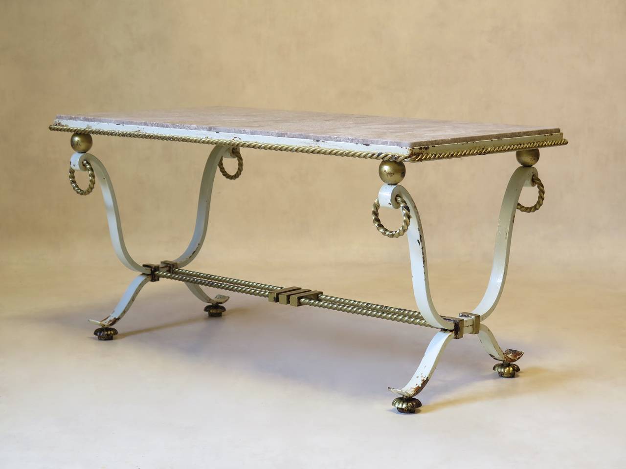 Rectangular coffee table almost certainly by Gilbert Poillerat, in cream and gilt wrought iron. Twisted rope detailing around the original pink or grey marble top. Spheres and hanging ring detail.