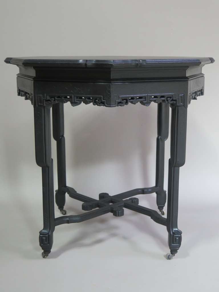 Octogonal side or centre table with carved apron. Interlocking stretcher. On casters.