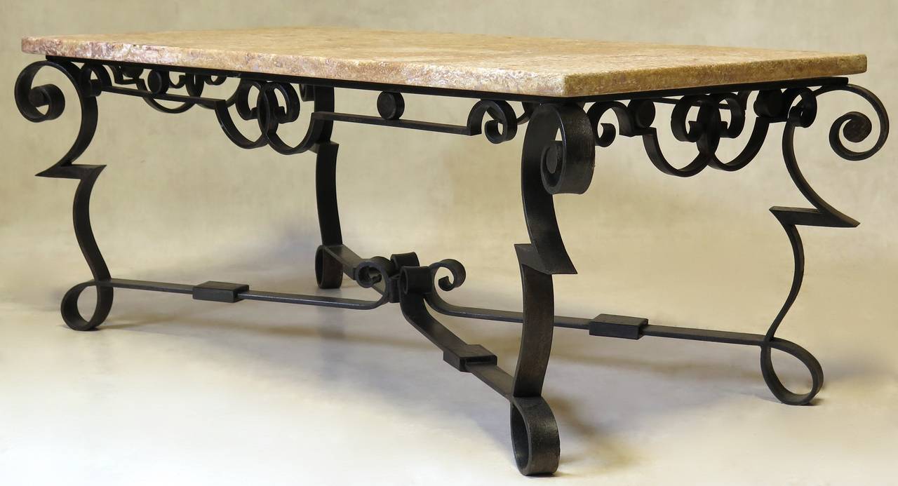 Elegant Art Deco-period wrought iron coffee table with a marble top.

Bold lines, with contrasting graphic zig-zags and elegant loops and scrolls.

The marble top is pink and yellow veined with white.
