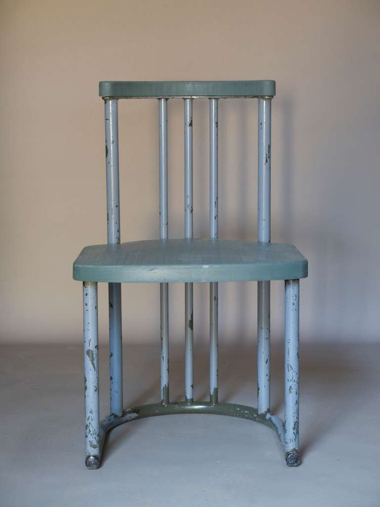 Set of five chairs with sturdy tubular metal structures painted grey with a dark kaki green colour showing through. U-shaped bases and curved backs. The seats and crest rail are fitted with wood, painted grey/green.

Minimalist and well-thought