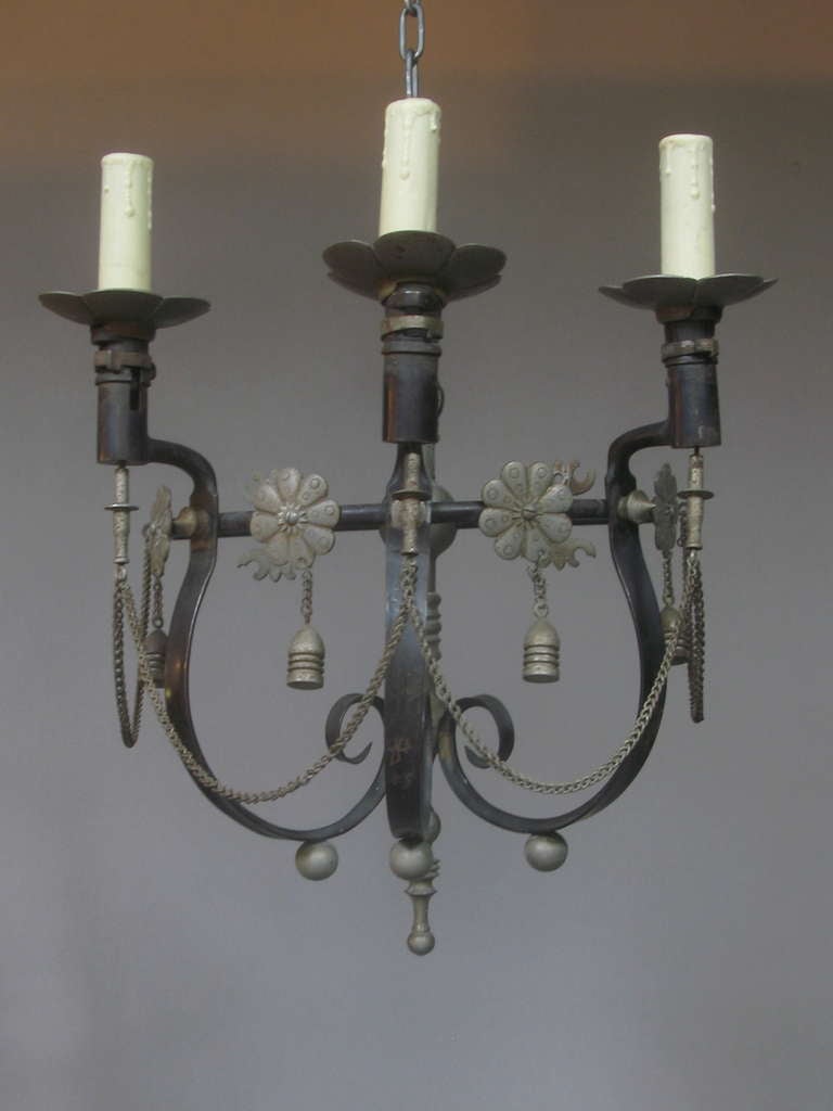 Very rare pair of sconces, made out of antique bayonets that have been bent into scrolled arms.

Highly decorative, adorned metal stars, rosettes and chains.

Each sconce holds three lights.