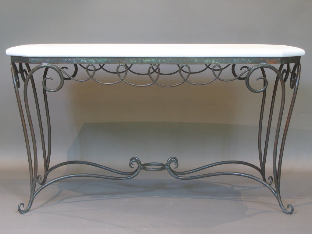 Elegant and heavy wrought-iron centre / console table base in the style of Rene Prou and René Drouet, with traces of red and green paint still just visible. 
The top is of Lens stone and is a slightly outwardly curving rectangle with cut corners