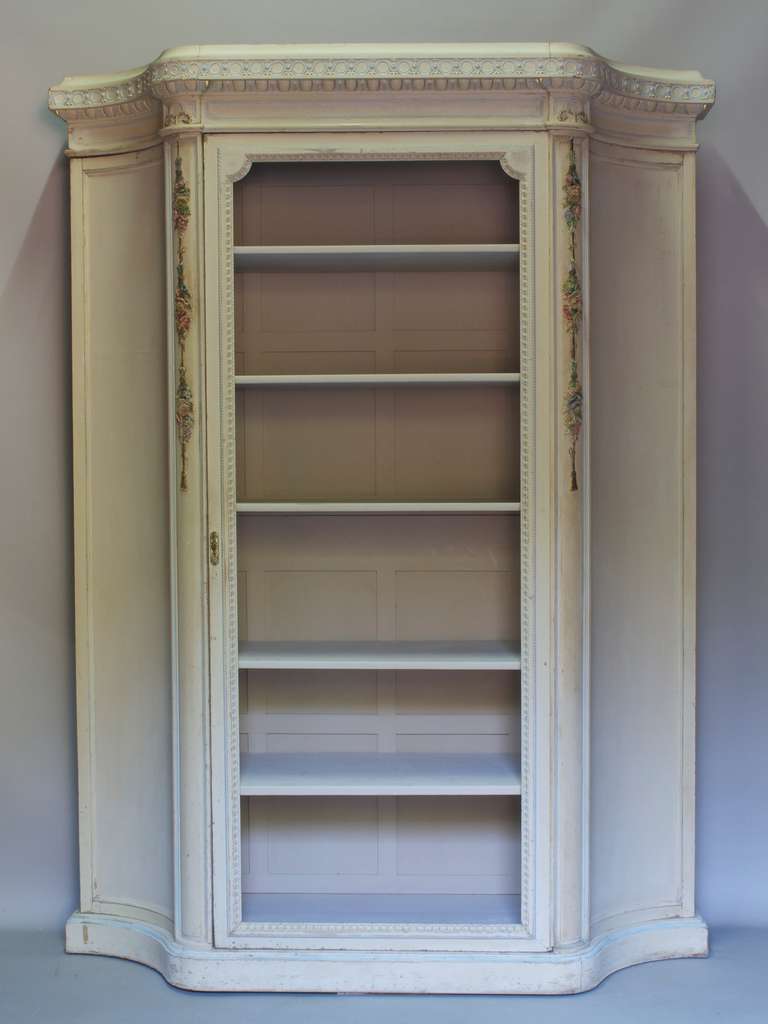 Unusual and very pretty armoire of large proportions, with concave sides, entirely carved out of wood. Cream-colored paint with light blue and gold details. The cornice is decorated with a frieze of egg and dart motif. Carved floral detailing on