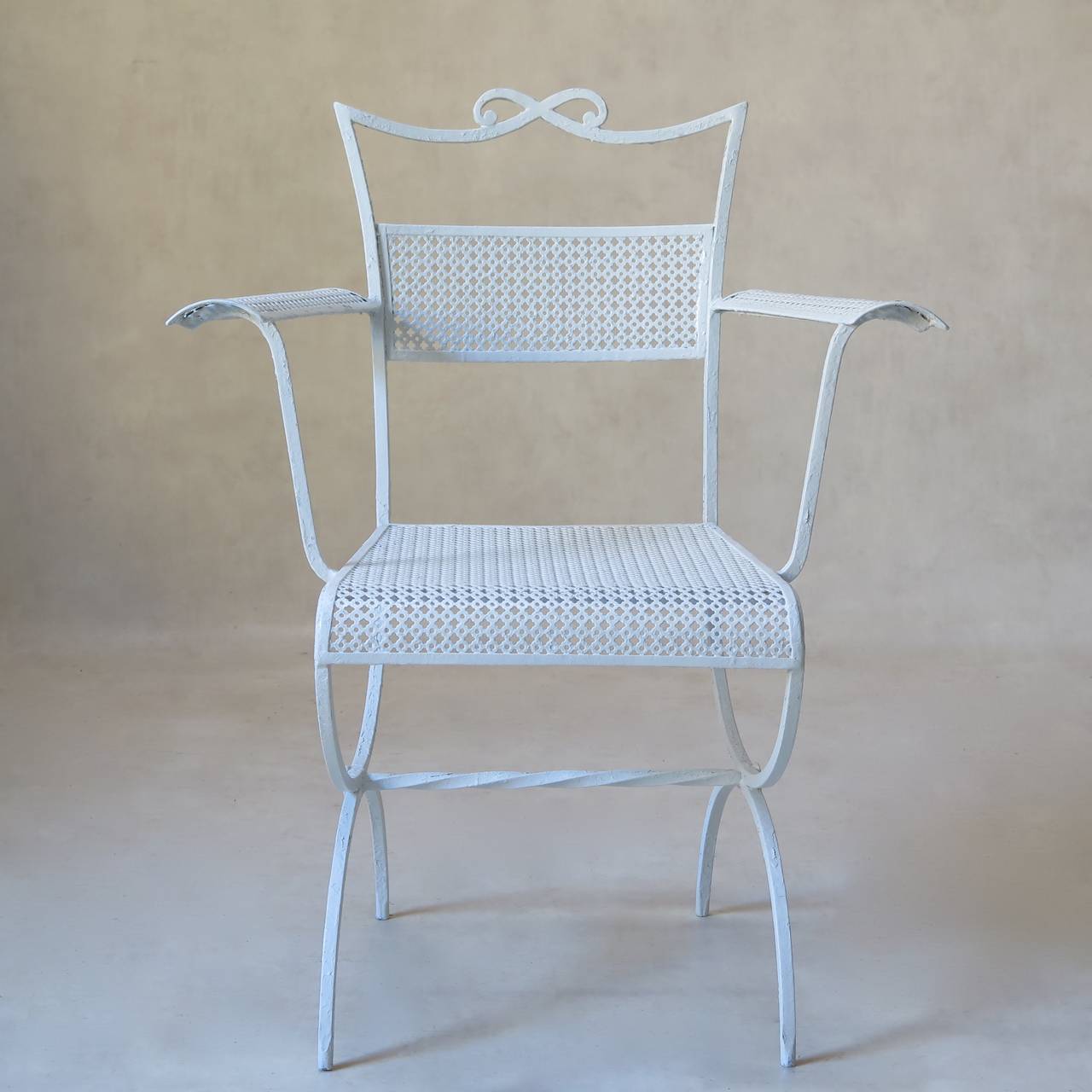 Charming pair of bow-motif wrought iron armchairs by Maison Jansen. Elegantly tapering backs, with a bow on crest rail. Curved armrests and seta edge. Curule-shape bases, joined by a twisted iron stretcher. The seats, backs and armrests are made out