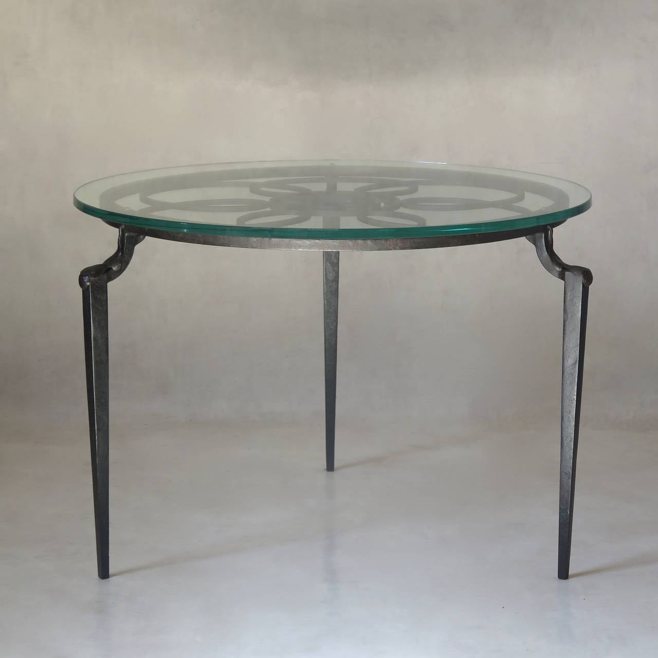 Elegant small round tripod coffee or side table with a hammered wrought iron base. Raised on tapering square legs of solid iron, the knees capped in wrought iron oak leaves, the center decorated with a central 