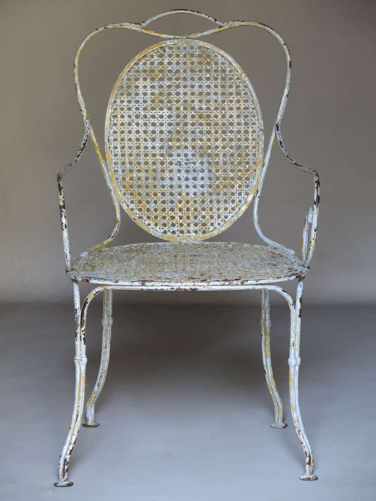 A timeless classic, with lovely wire-caned seats and oval backs, scrolled arms and elegant splayed legs. Original patina: light grey with previous yellow paint visible beneath.
Very sturdy and well-made.

For use indoors or out.