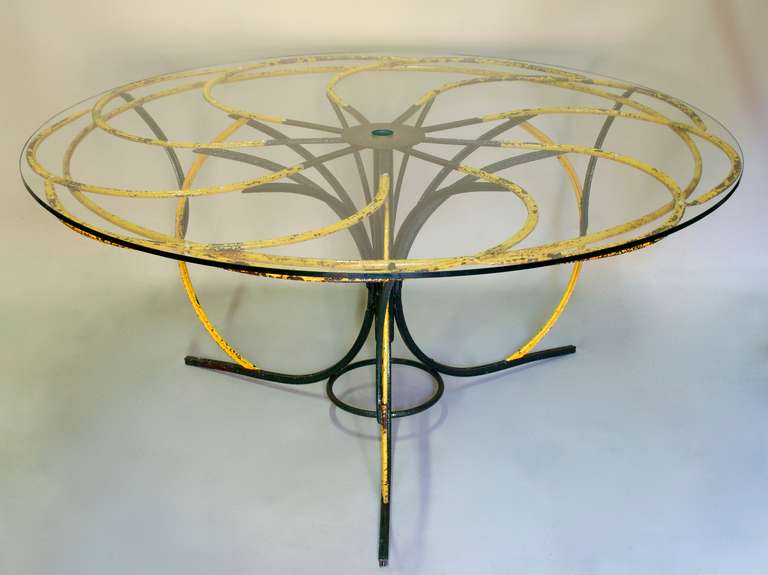 Unusual and lovely round wrought-iron folk art dining table with the top shaped like a flower. 
Painted yellow and dark green.
Top fitted with new, thick-cut glass with hole in the centre to accomodate a parasol.