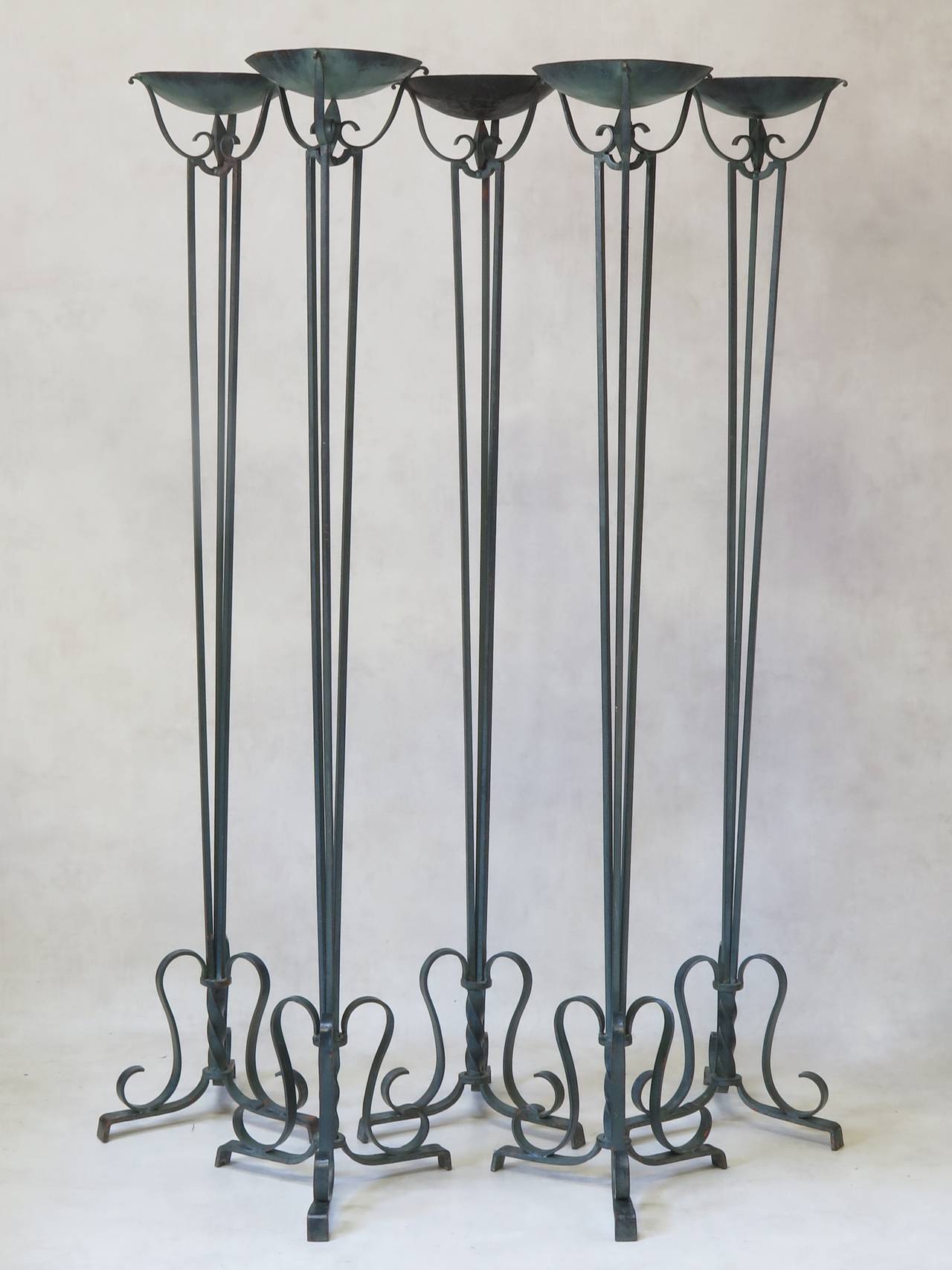 Elegant set of five French Art Deco neoclassical wrought iron torchères or candleholders.
The cupola is supported by a long tapering stem made up of three iron rods. Tripod base.
Bronze like verdigris paint finish, with orange primer visible
