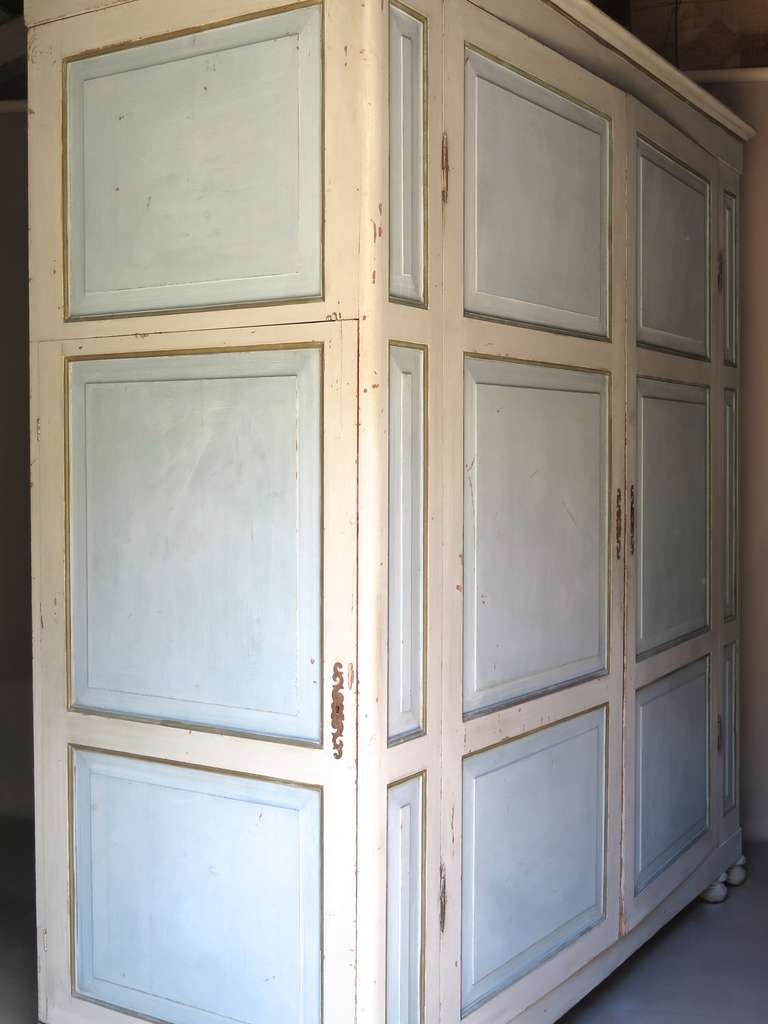 Very large and deep paneled Italian armoire painted a delicate robin's egg blue and cream color with gilded accents, supported by bun feet. It is unusual in that there is a door at each side as well as the two front doors.

Elegant and