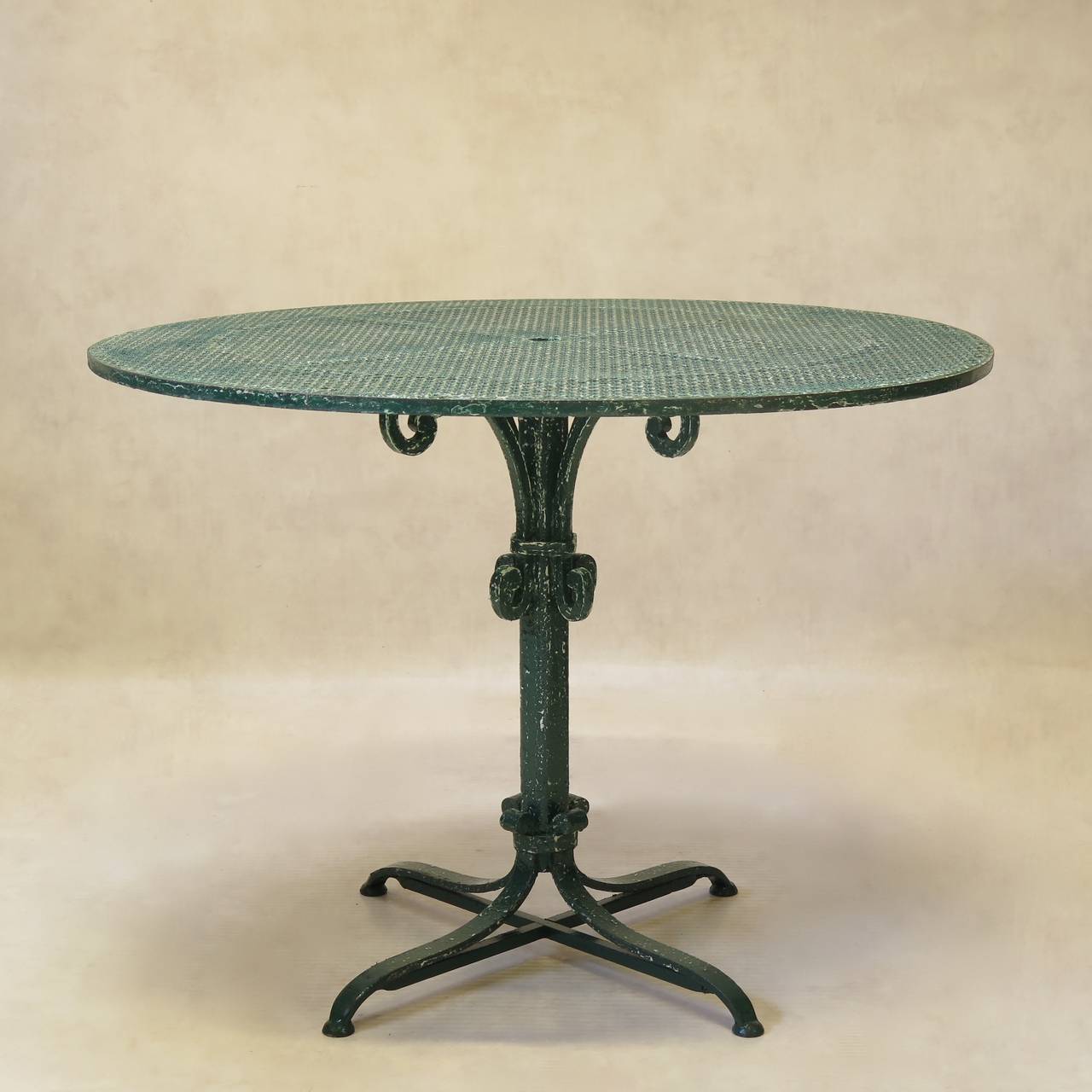 Almost-pair of round wrought iron outdoor dining tables, with cloverleaf-patterned tops and stem bases. Painted in classical garden green colour.

Very slight difference in size, as well as in the shape of the base.

 Dimensions provided below