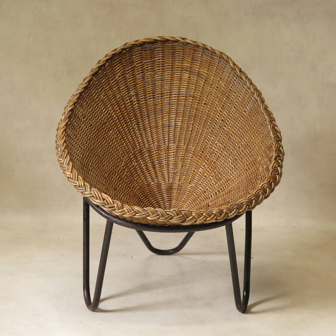 Unusual and funky lounge chair with a tripod solid iron base and sturdy conical, egg-shaped wicker seat.

