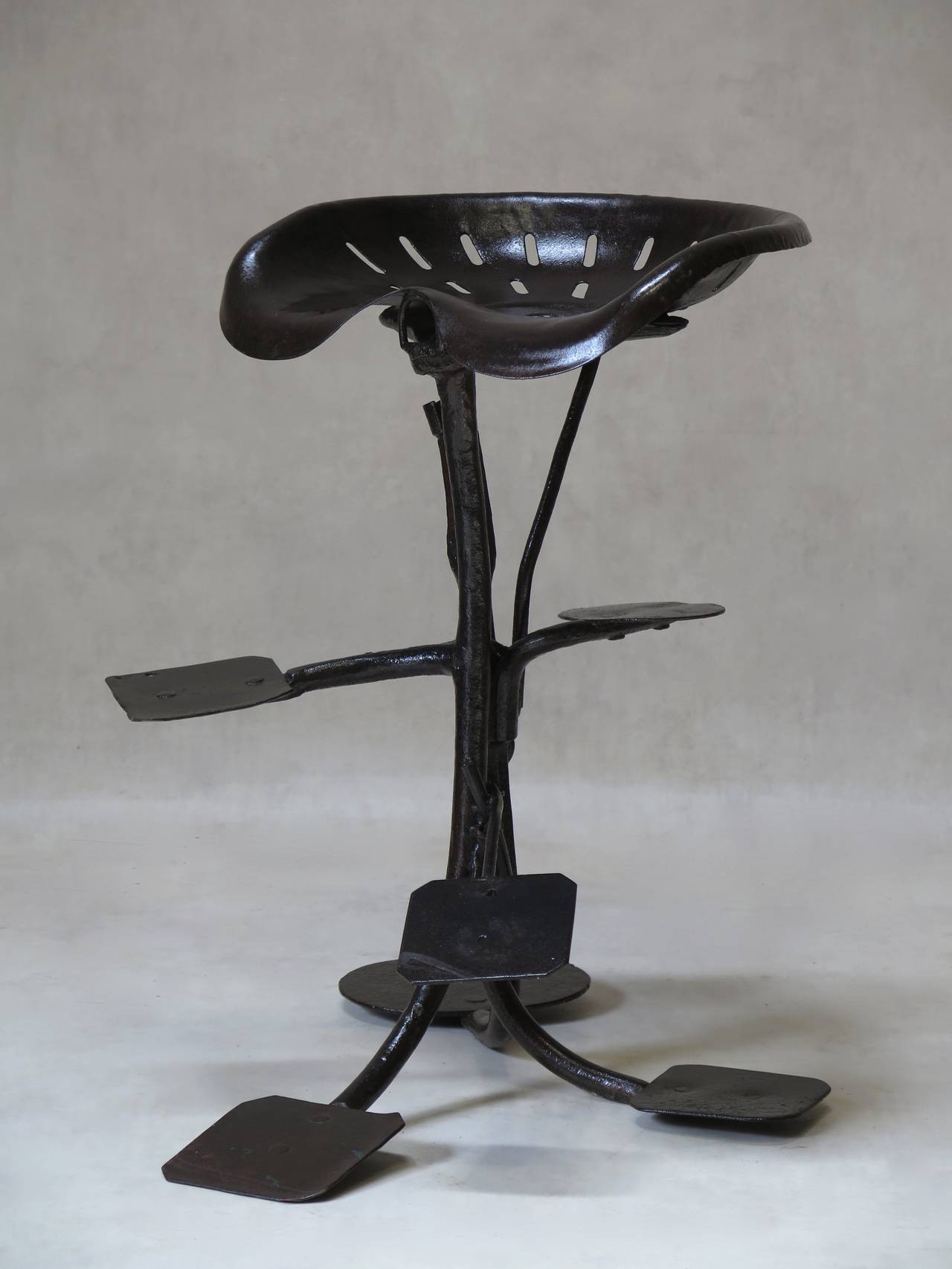 Unique sculpturesque artist's stool made out of assembled wrought iron tractor parts.