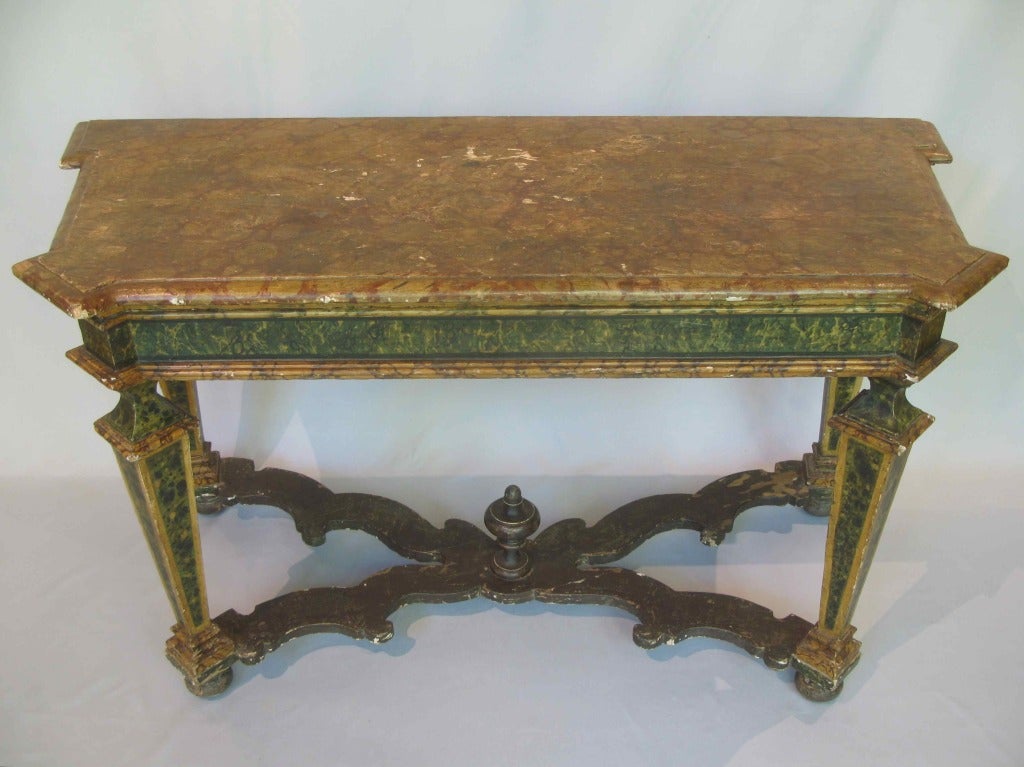 Very elegant Italian console table, entirely hand-painted with a marble trompe-l'œil. The top is of trapezoidal shape, with the corners jutting out. The square, tapering baluster legs are joined by an X-shape stretcher, topped with a large central