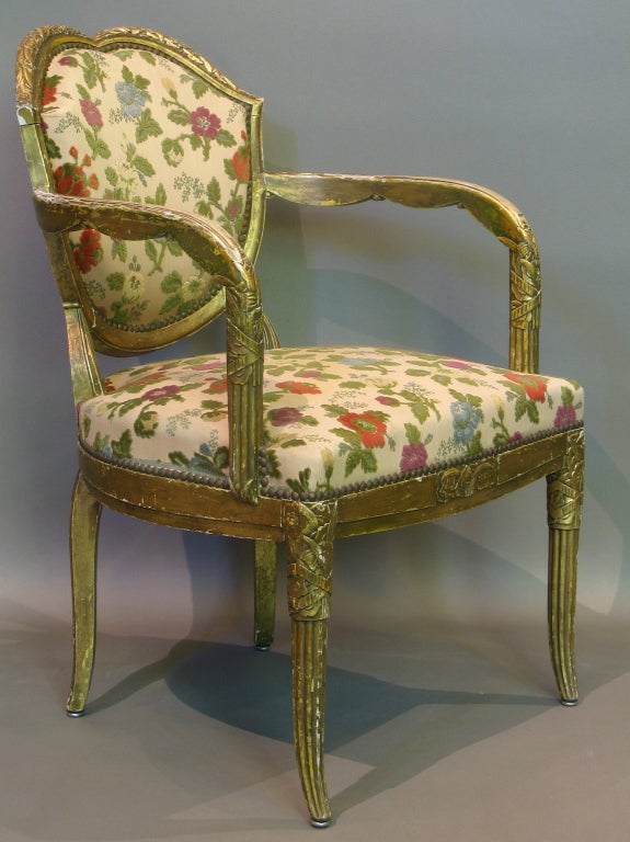 Rare and wonderful set of three early Art Deco gilded armchairs, carved with stylised floral motifs. 
Unusually shaped backs. 
Swag detail on arms. 
Delicately splayed cabriole legs. 
Reeded front legs. 
Original floral upholstery in very good
