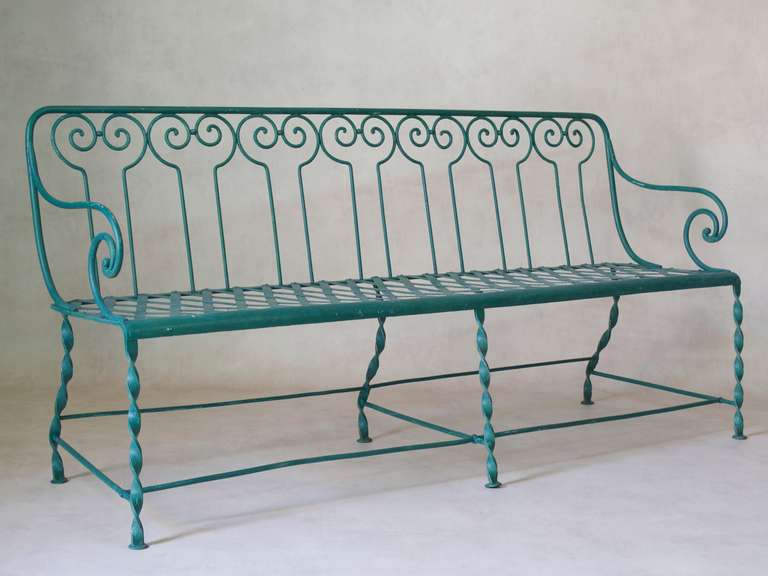 Classic turn of the century French garden bench made of wrought and twisted iron, with a criss-cross seat, elegant back design and scrolling arms.