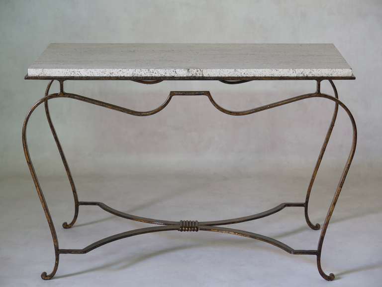 Low rectangular table with elegantly stylized cabriole legs and apron, and a curving X-shape stretcher. The travertine top is raised.