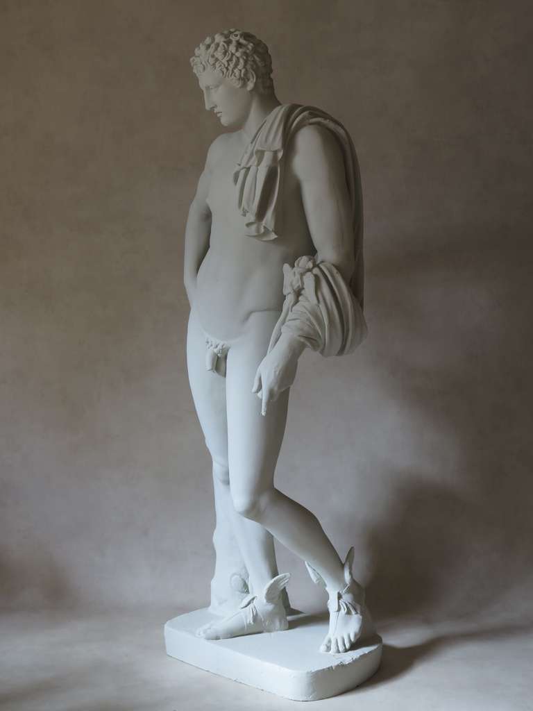 Fun and realistic statue of Greek god Hermes, recognizable by his attributes such as the winged sandals and the caduceus he is holding. 

Made of resin and painted a chalky, plaster-like off-white.