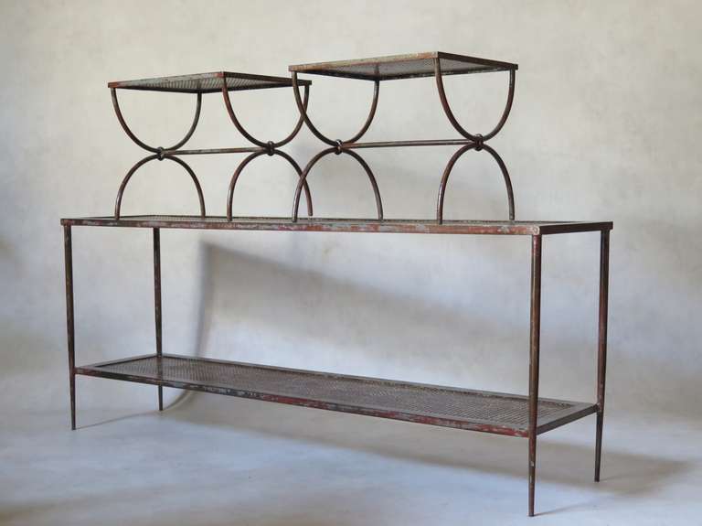 Wrought-iron set comprising a two-tiered long and lean console with elegantly tapering legs, and a pair of curule-based stools or side tables. The tops are of clover-leaf patterned sheet metal.

Wrought-iron, with traces of grey and red