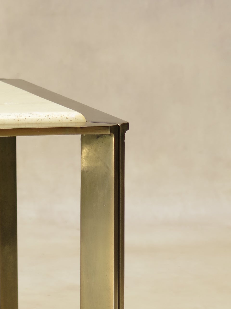 Chic and minimalist coffee table. Brushed steel structure with gold-coloured finish, and a light travertine top with rounded edges.