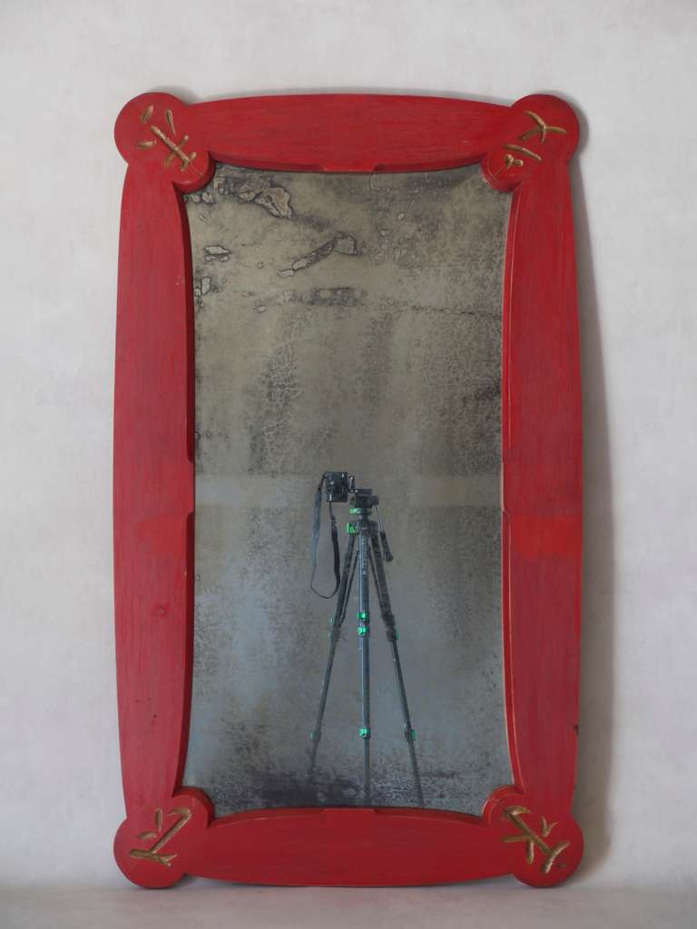 Large Chinese Art Deco style mirror with a wooden frame painted red and engravings picked out in gold at each corner.

Distressed mirror.