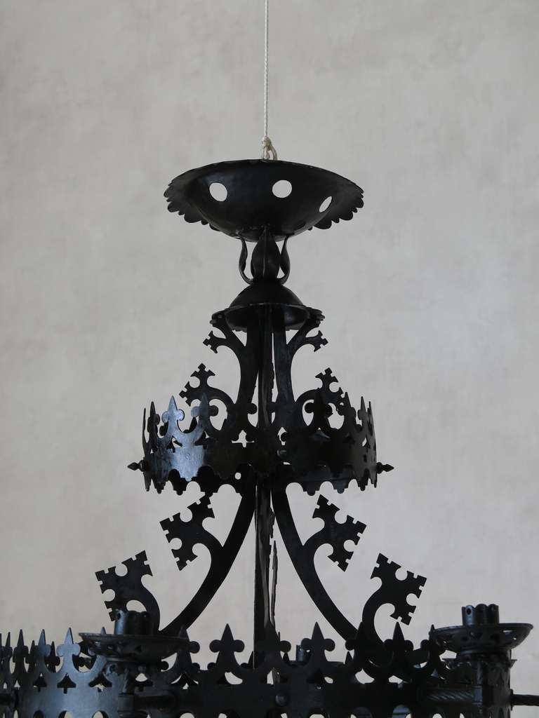 A rather impressive chandelier in the Gothic style, fashioned out of black metal.

Decorated with elaborate cut-out motifs.

Delicate and striking.