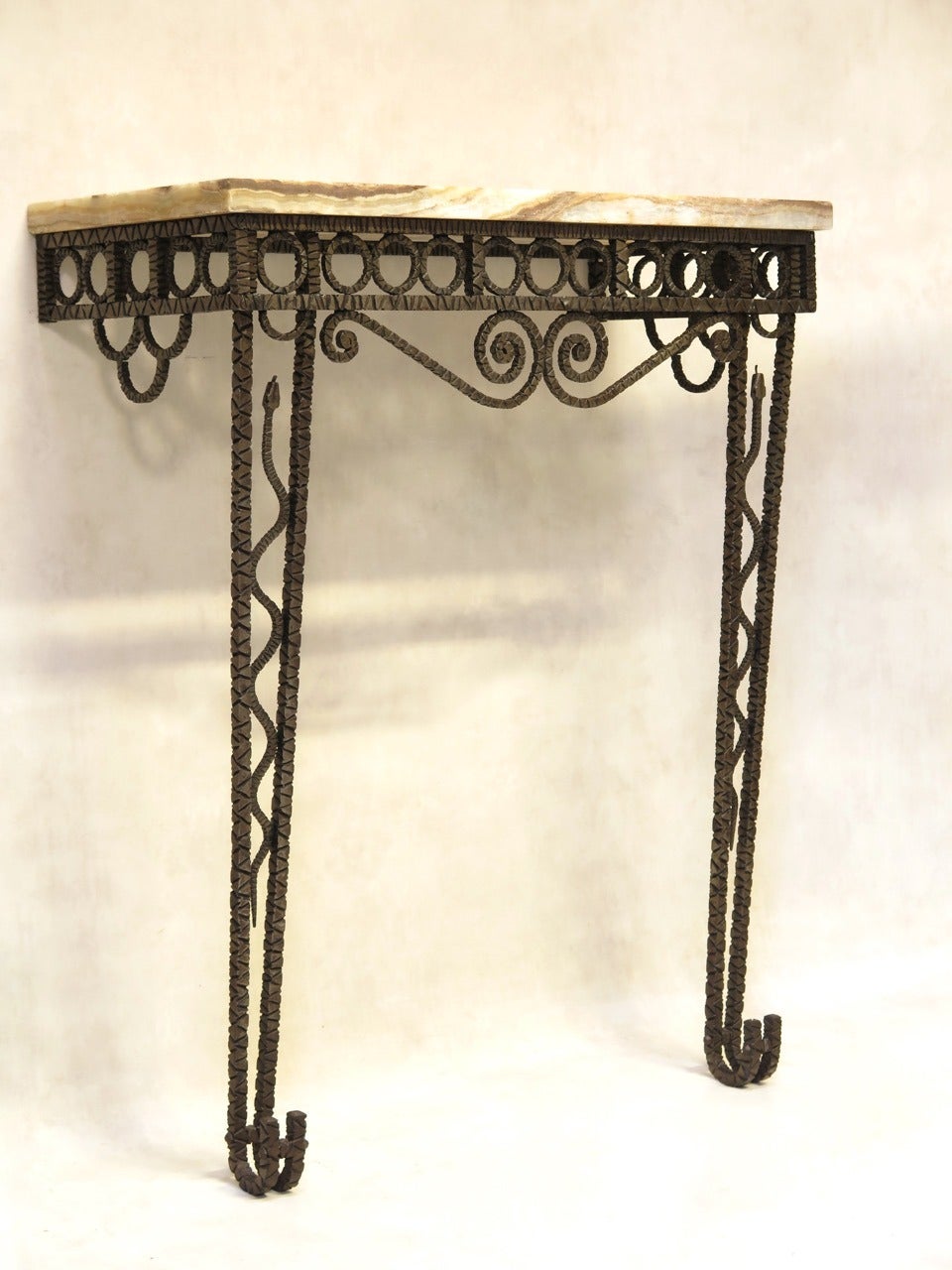 Striking Art Deco console in hammered wrought-iron with a decorated with a snake on each leg. The tapering legs end in elegant outwardly upturned feet. The apron is decorated with a frieze of circles, and scrolling arabesques. The top is made of a