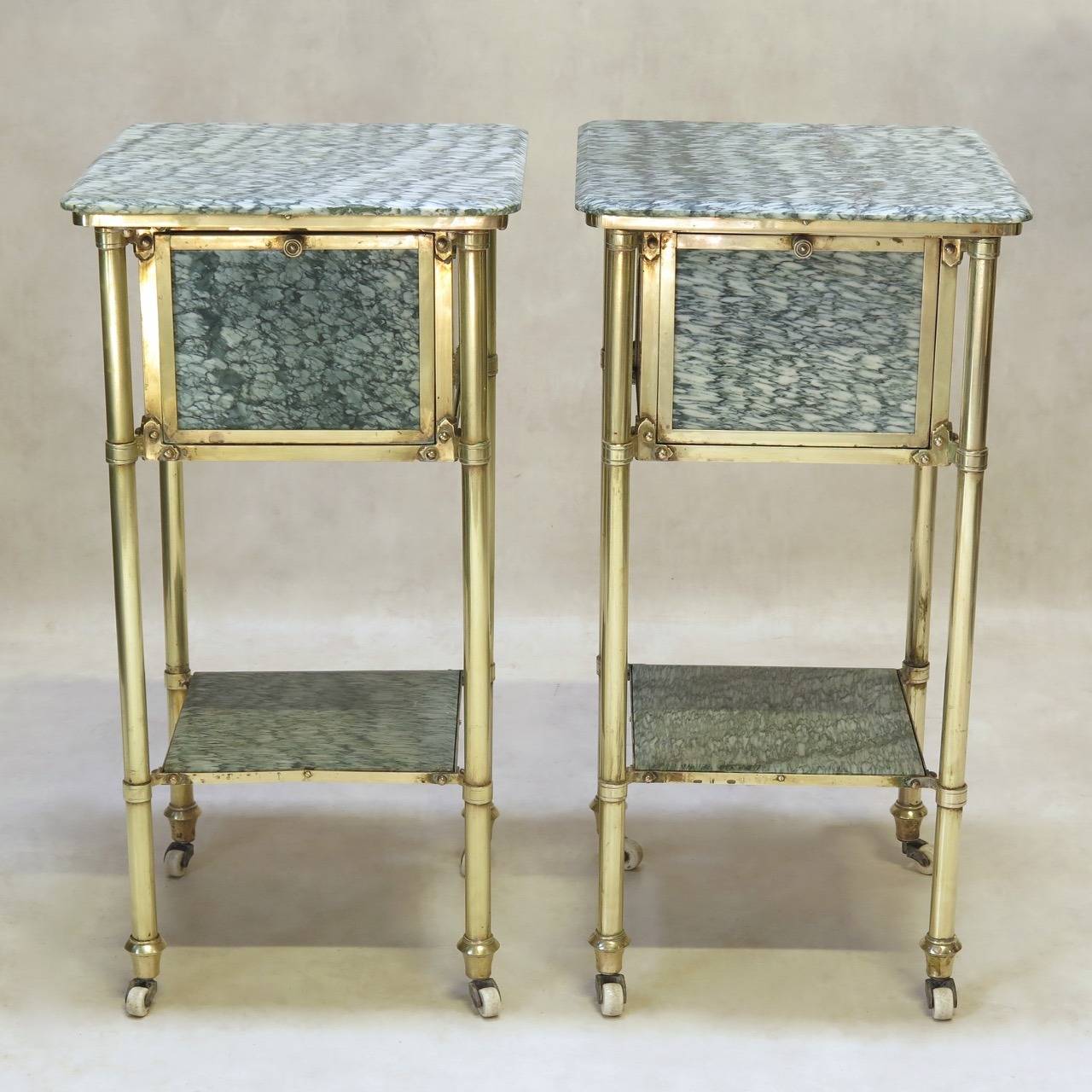 Very chic and nice quality pair of night stands / side tables with a solid brass structure, and rare Campan marble tops, drop-front cabinets and lower shelves. Raised on white porcelain casters.