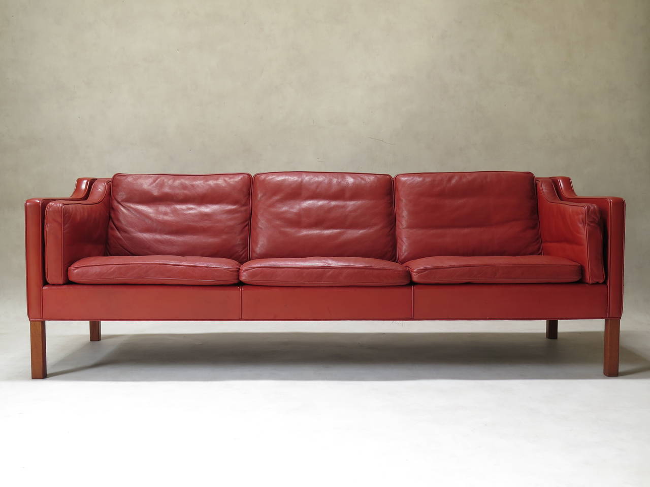 Chic and comfortable model 2213 three-seater sofa, designed  by Borge Mogensen in 1963. The sofa is upholstered in superb quality, soft leather of a rare, rich reddish-orange colour. The legs appear to be made of teak. The cushions are down-filled,