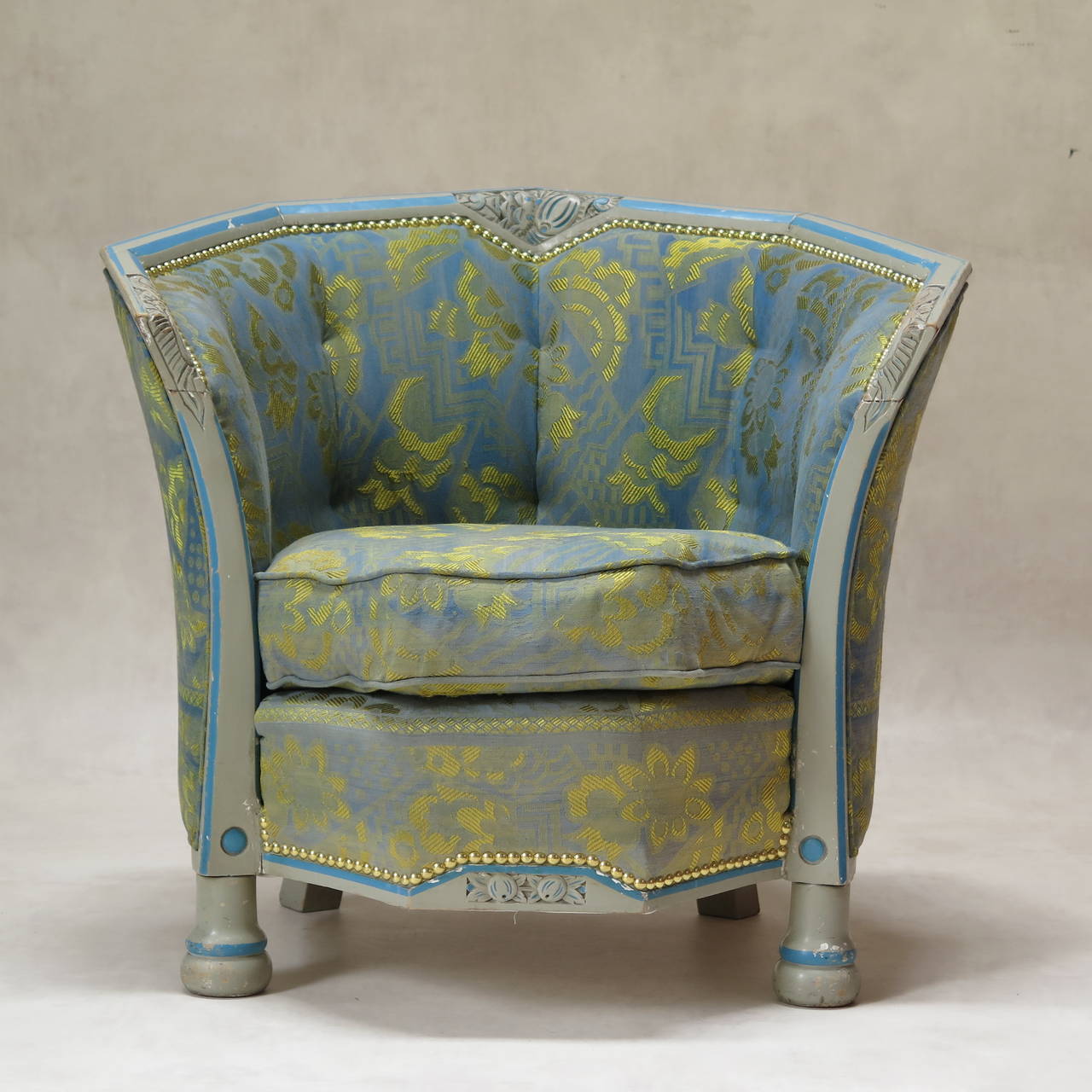 Charming and unusual Art Deco bergere, based on a nine-sided design, the back and sides opening upwards and outwards like a corolla. The wood frame is carved with stylized floral motifs and painted light grey with details picked out in blue.