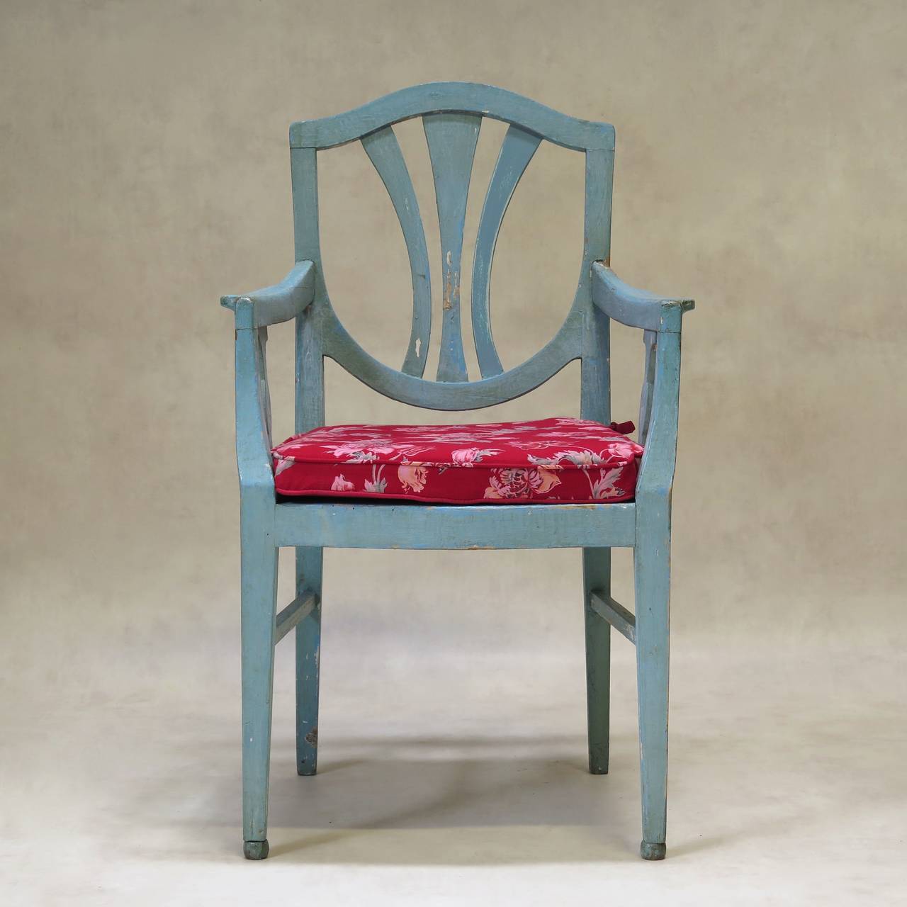 Charming set of two chairs and two armchairs with shield-shape backs, painted robin's egg blue. The front legs end in ball feet. The seat cushions are covered in lovely printed cotton, with a floral pattern on a red background.

Dimensions
