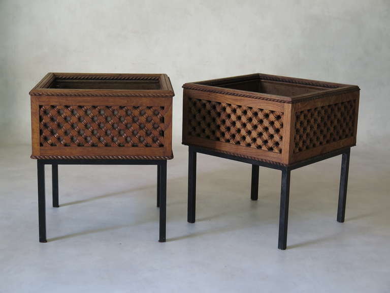 An elegant pair of square planters. A wooden casing with intricate latticework fits over a copper container. Supported by black metal bases.