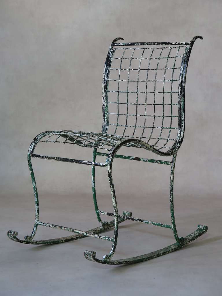 A charming one-of-a-kind wrought-iron rocking chair with a lovely curving design.

Traces of old white and green paints.