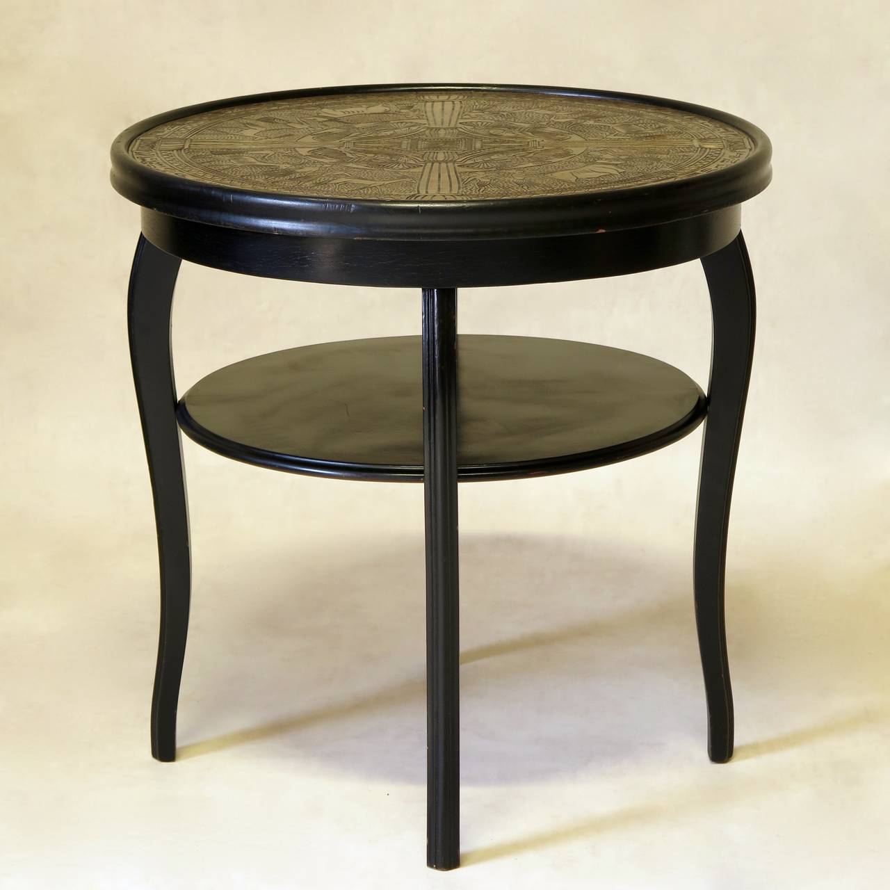 Chic two-tiered round side table with an ebonised wood structure. The top is of repoussé copper with an egyptian-inspired motif.

Possibly Austrian (Thonet).